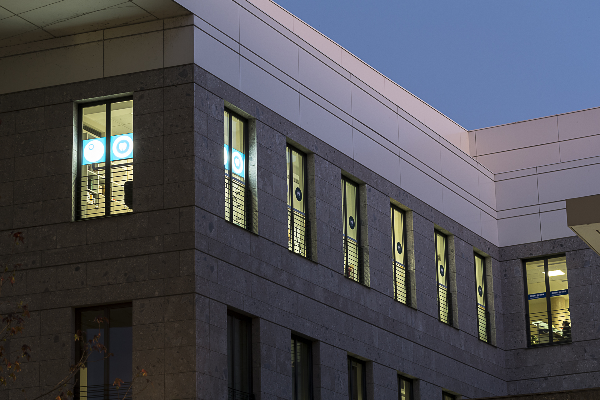 Il palazzo che ospita lo studio, di sera, con le finestre illuminate e il logo del dente
