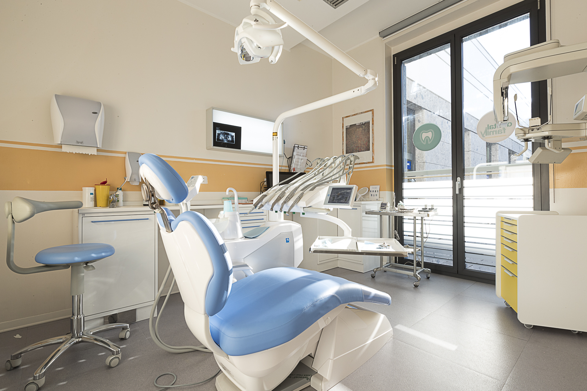 Una sala di cura dello studio, con il riunito azzurro, la finestra e le pareti color crema e giallo